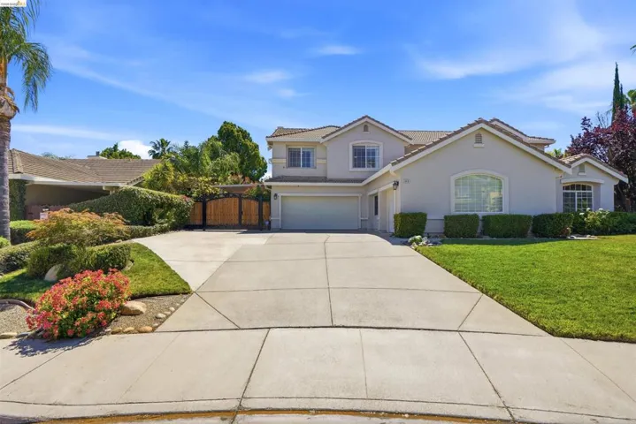 Two-story stucco residence with an arched entry window, an attached two-car garage, and a concrete driveway