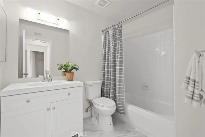 Guest bathroom has new paint, cabinet, mirror, toilet and flooring.
