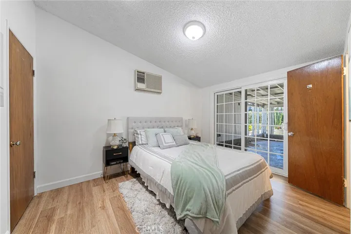 Primary bedroom has a solar light tube and wall AC. Sliders to the covered patio. Door to the right opens to the primary bathroom.Door to the left is the closet. Newly painted and newly installed vinyl plank flooring.