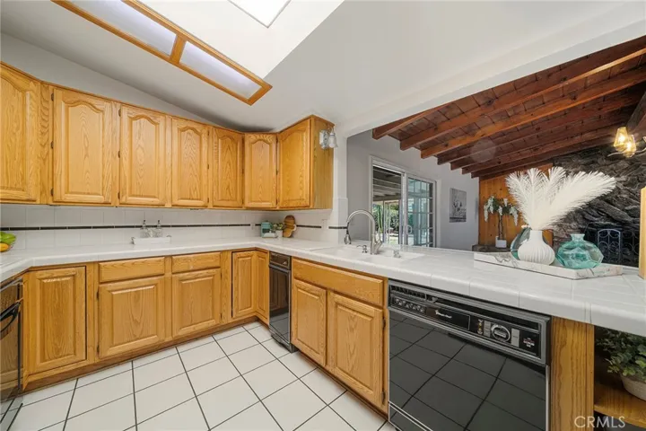 Plenty of cabinets and counter space to create your favorite meals. Casual dining area at the counter that flows to the family room with beamed ceilings. Sliders to covered patio.