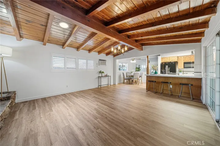 Roomy and inviting family room with beamed ceilings. Space to dine casually at the kitchen counter. Sliders to covered patio. Wall AC. Newly painted and newly installed vinyl plank flooring.