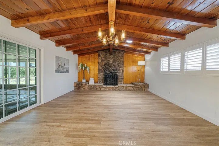 Very spacious family room with rustic charm having beamed ceilings, rock fireplace, and wood walls help create a warm and inviting room to enjoy. Sliders to the covered patio. Newly painted and newly installed vinyl plank flooring.
