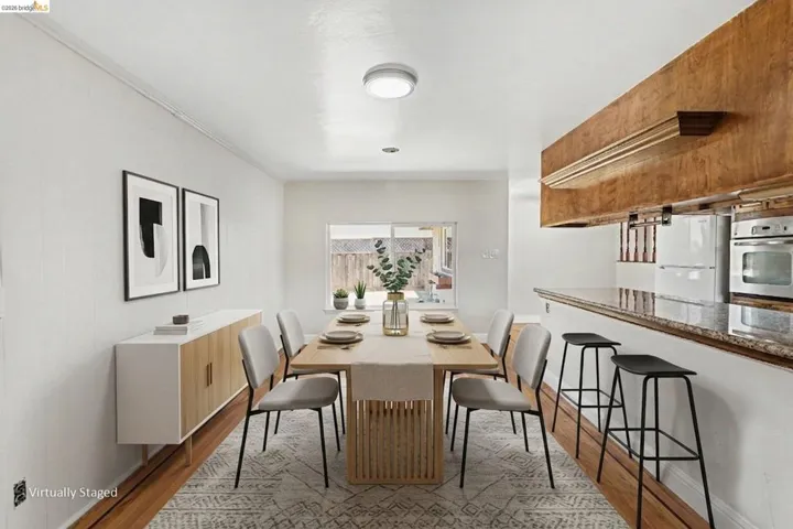 Bright dining area featuring wood-finish flooring, a pass-through counter with a stone-finish surface, and an integrated oven