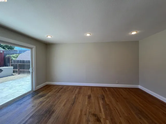 Spacious interior featuring wood-finish flooring, recessed ceiling lighting, light-toned wall paint, and white baseboards
