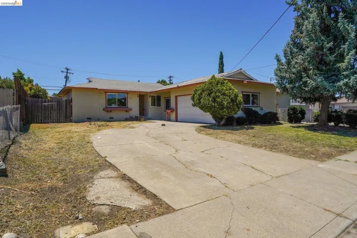 Single-story residence featuring a concrete driveway, an attached garage, and a fenced side yard