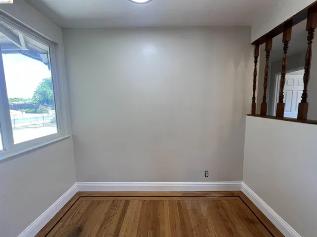 Hardwood flooring with border inlay, white baseboards, and a large window providing ample natural light