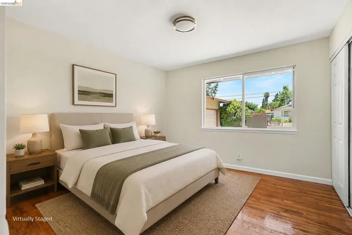 Hardwood flooring throughout featuring a large window with exterior views, white walls, and a ceiling-mounted light fixture