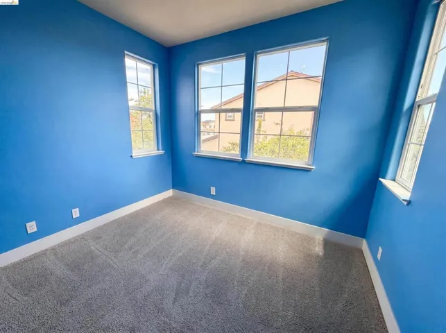 Bright room featuring five windows with white trim, light gray patterned carpeting, and white baseboards