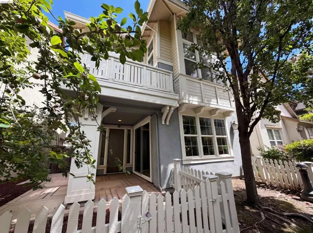 White picket fence entry leading to a covered porch with decorative corbels