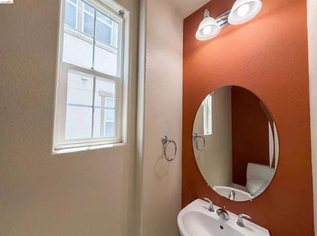 Powder room featuring a wall-mounted sink, a round frameless mirror, and a two-light vanity fixture