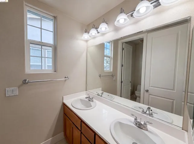 Bathroom featuring a dual vanity with white oval sinks, chrome faucets, and a full-width wall mirror