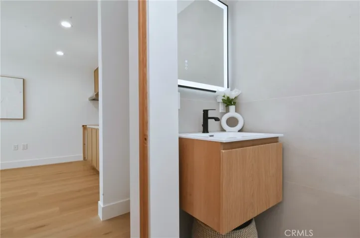  Modern ADU bathroom vanity area featuring a stylish floating wood console, round mirror, and clean lines.
