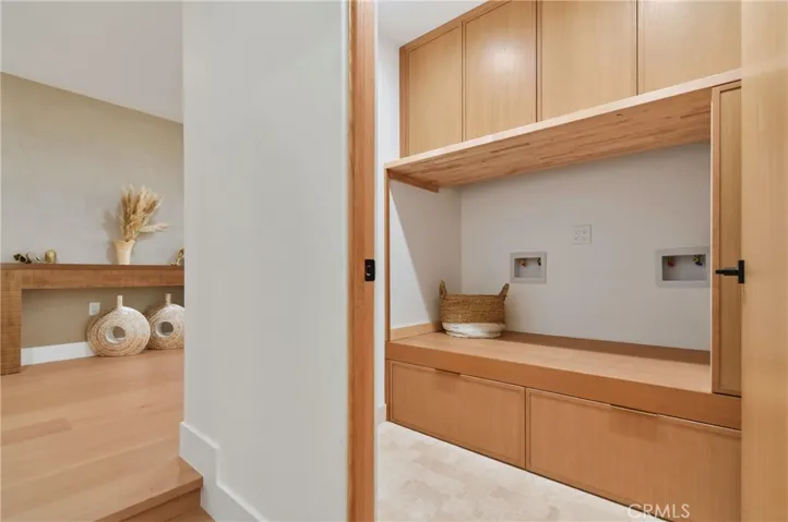 Sophisticated laundry room featuring premium custom cabinetry, extensive storage, and exquisite high-end designer tile flooring.