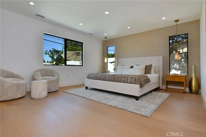 Spacious master bedroom with large windows, bright natural light