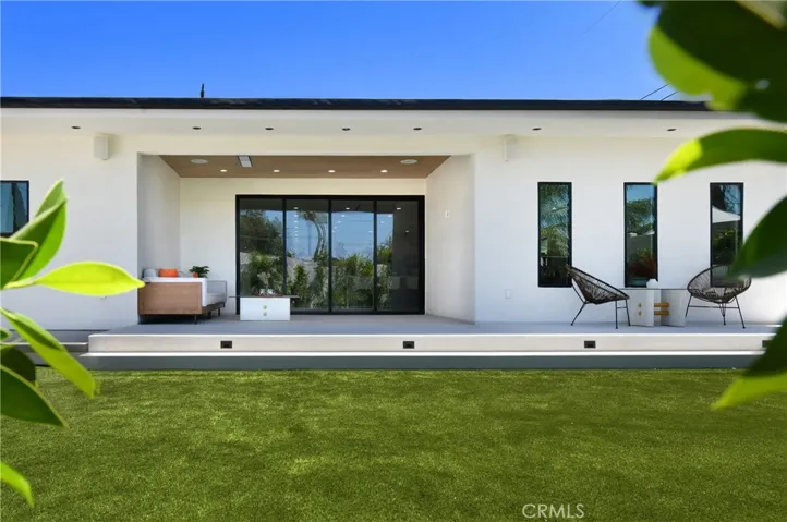 Centered view of the home's rear exterior, showcasing large glass sliders and pristine landscaping.