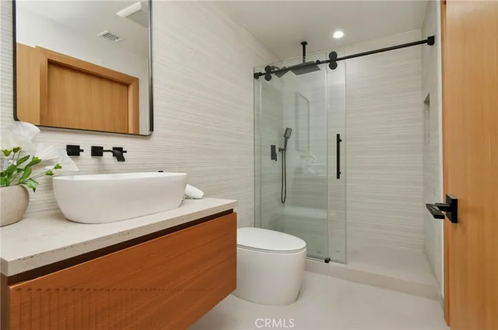 Sleek guest bathroom, features luxury smart toilet with integrated lighting and advanced features, complete with modern tiling, a crisp white vanity, and premium finishes