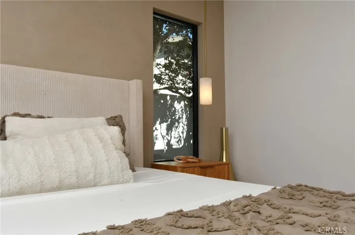 Elegant bedroom showcase featuring a textured Roman clay accent wall, flanked by beautiful identical windows on each side of the bed. Complemented by custom ceiling and side accent lighting.
