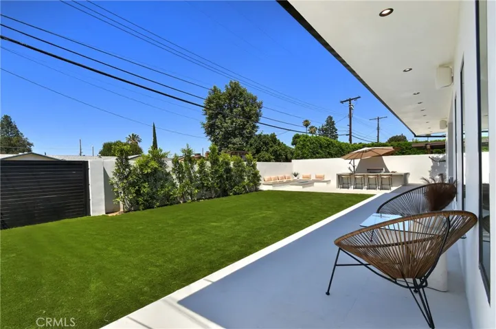 Sunny backyard view capturing the vibrant green lawn, privacy hedges, and secondary patio space.