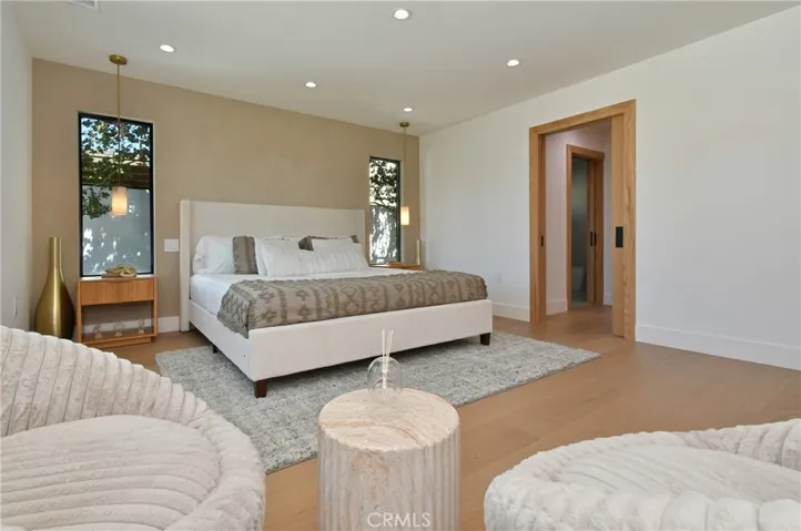Expansive bedroom suite showcasing a clean design, a Roman clay accent wall, recessed lighting, and a neutral color palette.
