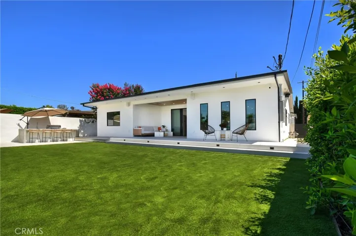 Wide view of the property's clean, modern lines against a beautifully manicured lawn. With a build-in BBQ and a bar seating area. with the space for a swimming pool - if desired
