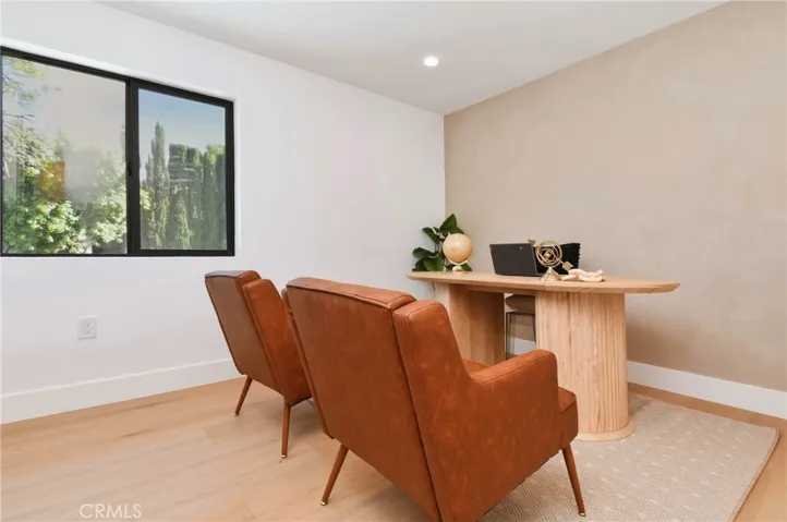 Versatile ADU bedroom or home office space with large windows offering great natural light and views of the greenery, featuring textured Roman clay accent wall.