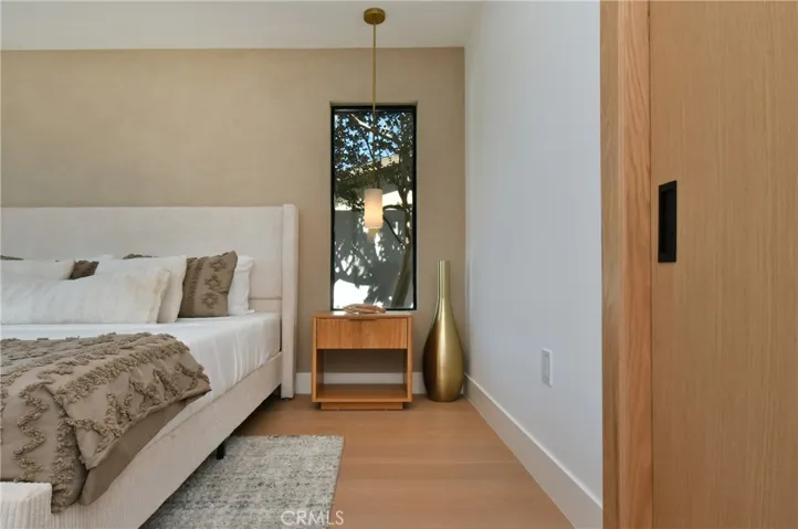 Bright and airy bedroom featuring warm engineered wood flooring and a minimalist, modern aesthetic