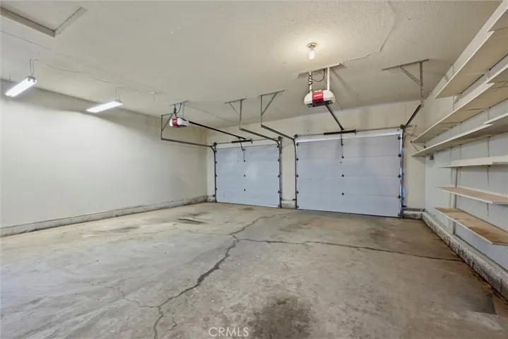 Spacious two door garage, with man door at the left to outside.  Plenty of shelves.  Two garage door openers