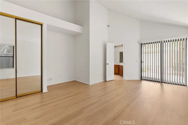 Primary room w/mirrored sliding closet door and vaulted ceiling
