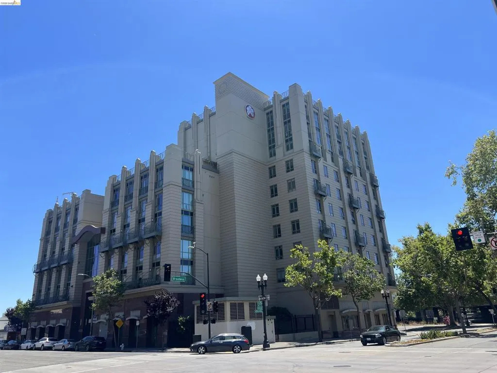 Multi-story building featuring an Art Deco architectural style, vertical window banks, individual balconies, a light-colored facade, and a prominent corner location