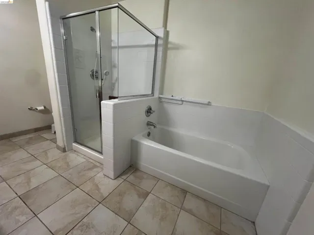 Bathroom featuring a glass-enclosed shower, a built-in bathtub with white tile surround, and large format floor tiling