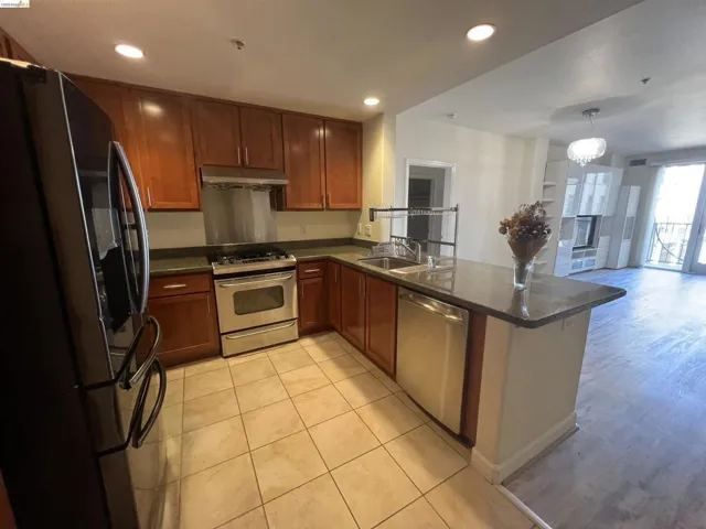Kitchen featuring wood cabinetry, stainless steel appliances, dark countertops, and tile flooring