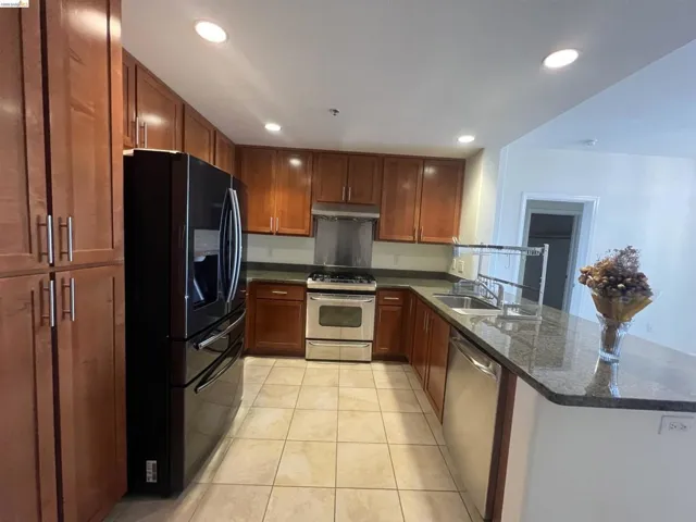 Kitchen featuring medium-toned cabinetry, granite-finish countertops, and tile flooring