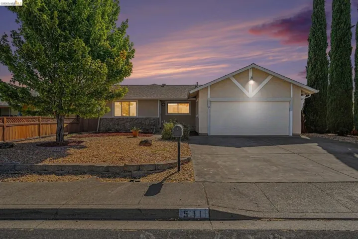 Single-story residence featuring a two-car garage, concrete driveway, and a front yard with a rock landscape