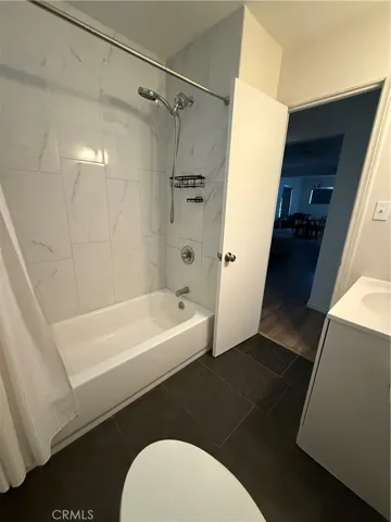 Full bathroom with tub, shower head, sink, and toilet.