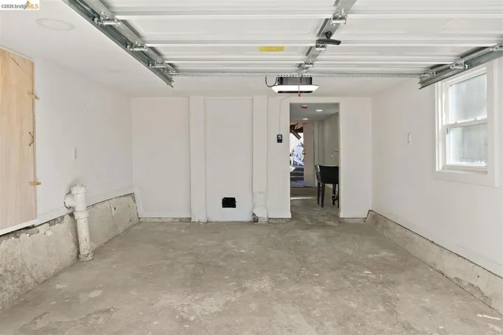 Spacious garage featuring a concrete floor, bright white walls, and a window for natural light