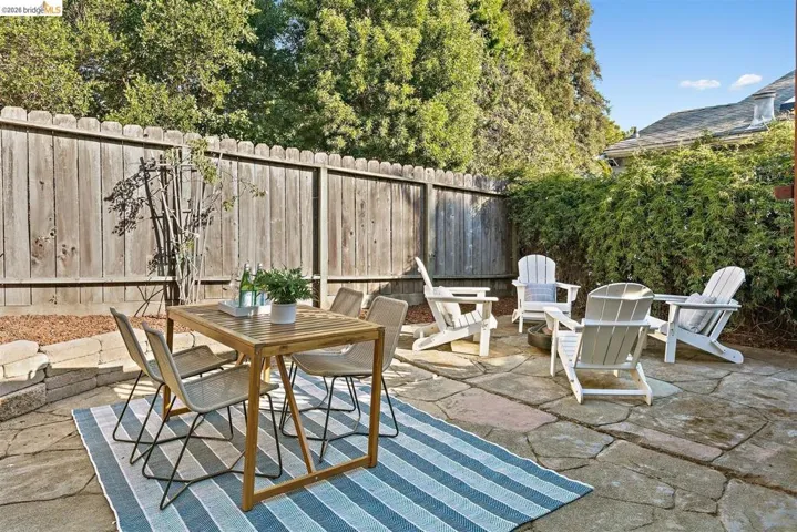 Expansive flagstone patio area featuring a private wood fence, mature perimeter shrubbery, and terraced landscaping