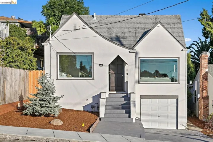 Gable-roofed stucco residence featuring a single-car garage, prominent front steps, and a decorative front door