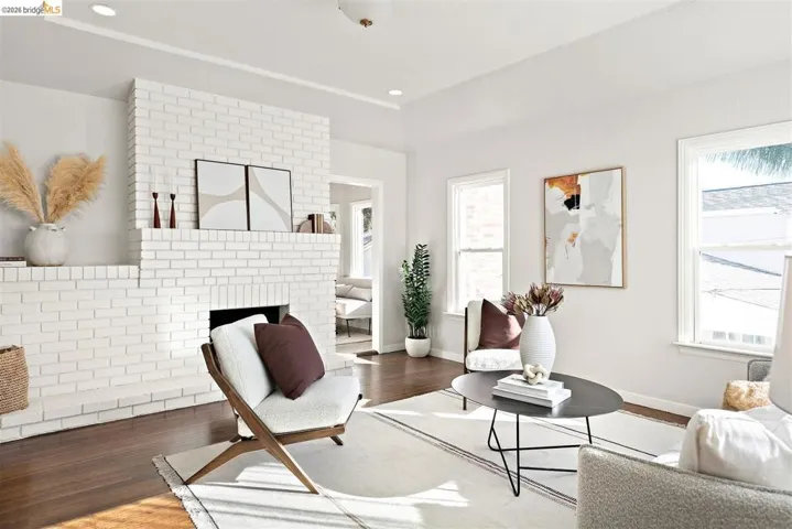 Living area featuring a painted brick fireplace, recessed lighting, wood-finish flooring, white walls, and multiple windows