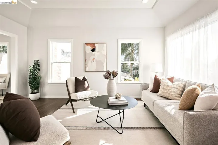 Living area featuring vaulted ceilings, recessed lighting, wood-finish flooring, and multiple windows providing natural illumination