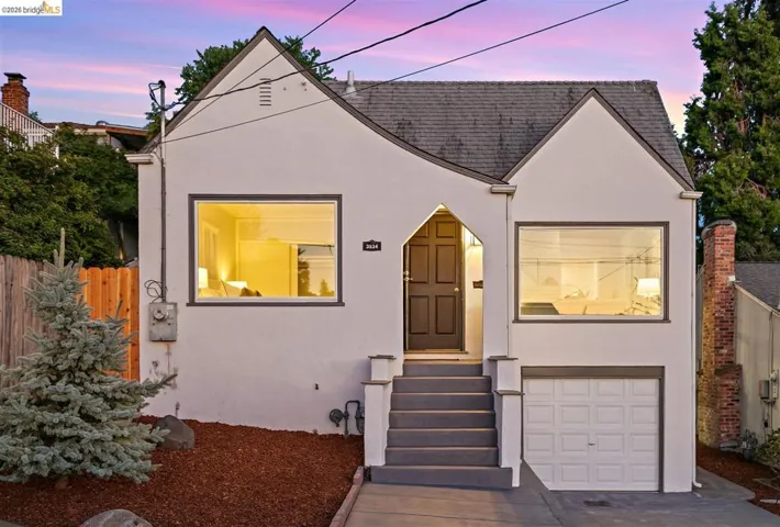 White stucco exterior featuring a dark gray asphalt shingle roof and a prominent front-facing gable
