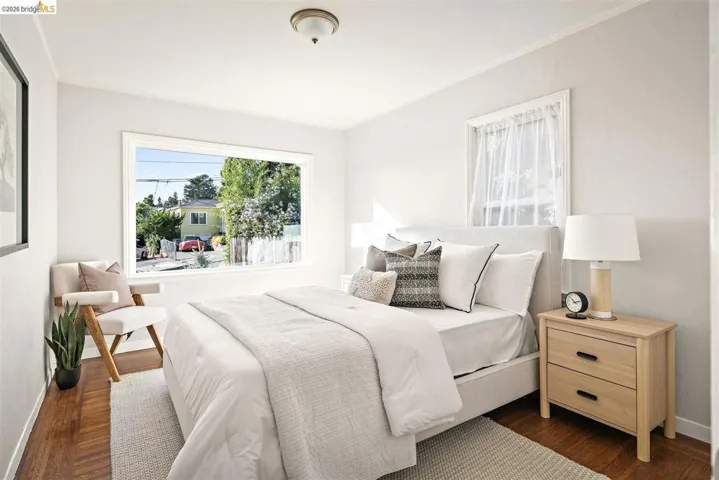 Bedroom featuring hardwood flooring, a large picture window, a secondary window, and a flush mount ceiling light fixture
