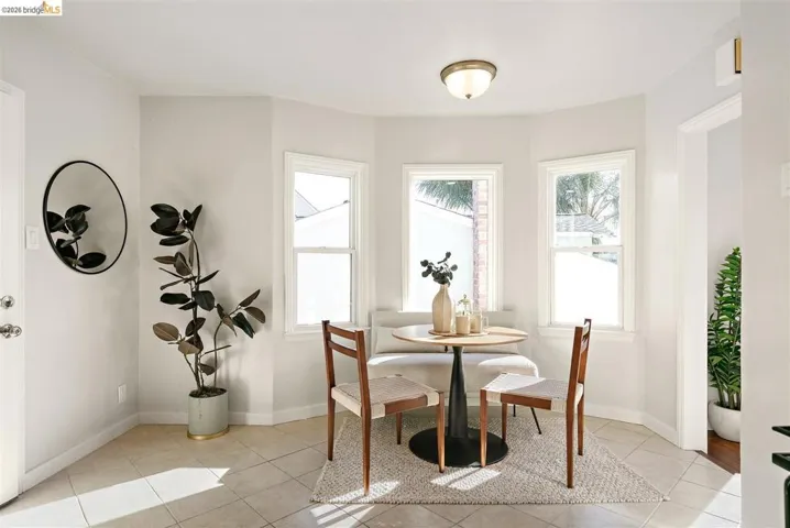 Bay window dining area featuring three single-hung windows, a flush-mount ceiling light fixture, and tile flooring
