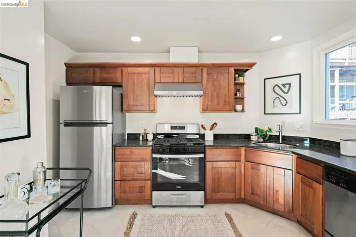 Kitchen featuring wood cabinetry, stainless steel appliances, dark stone countertops, and recessed lighting