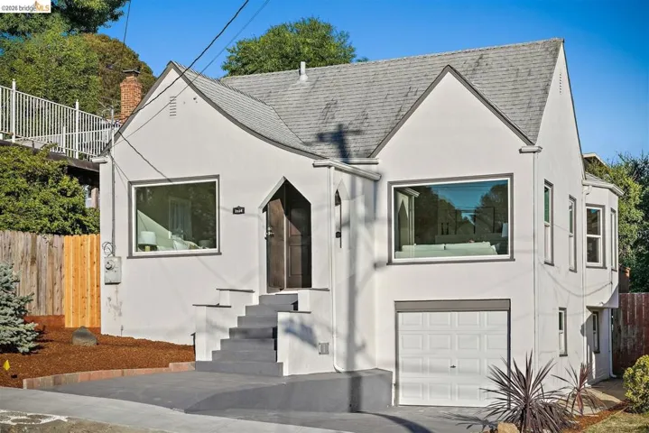 Stucco exterior featuring a prominent gabled roofline and an arched entry door