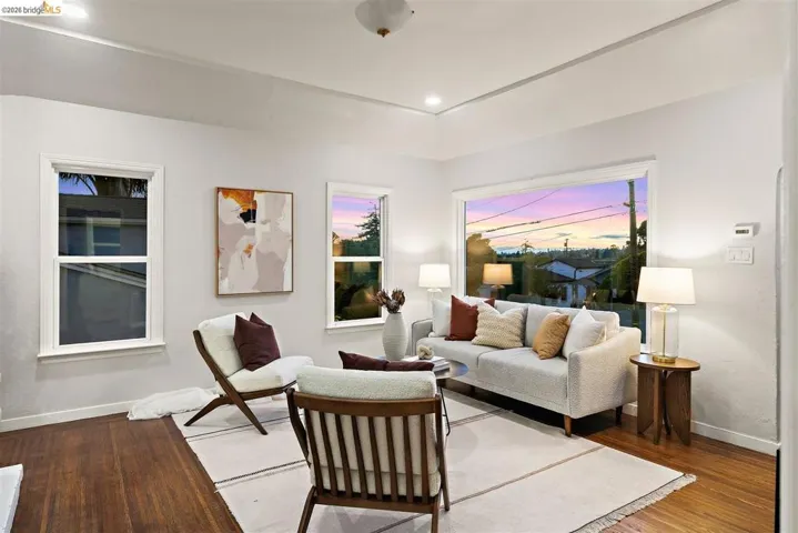 Spacious living area featuring large windows, wood-finish flooring, recessed lighting, and a tray ceiling