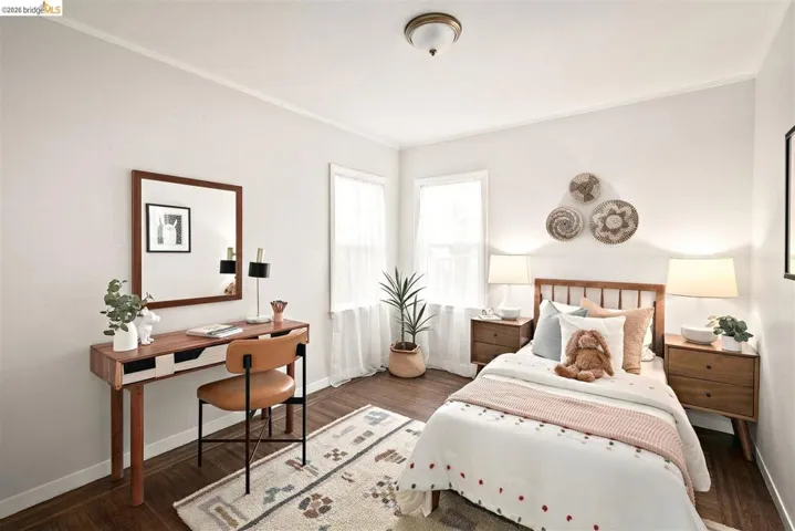 Bedroom featuring wood-finish flooring, two windows with natural light, and a ceiling-mounted light fixture