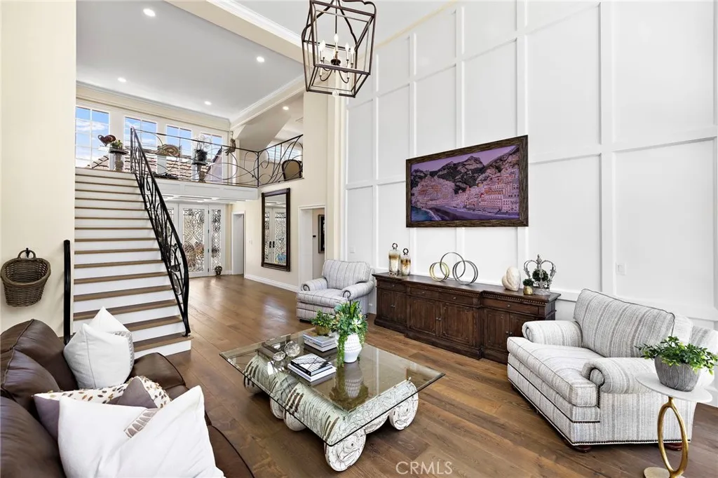 Living room with paneling and stairs with intricate wrought iron staircase