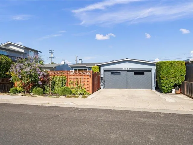 Inviting front exterior with lush flowers and a fence leading to a private patio retreat.