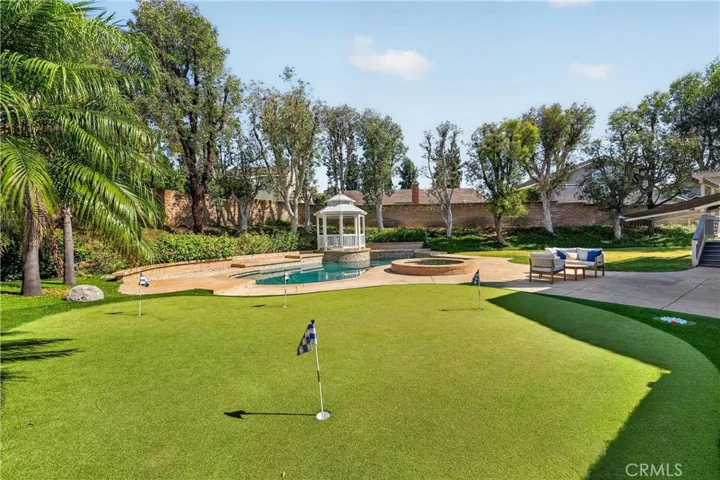 Resort-style backyard featuring a pool, spa, putting green, spacious patio, and gazebo, perfect for entertaining and relaxing