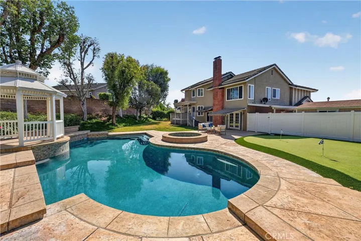 Resort-style backyard featuring a pool, spa, putting green, spacious patio, and gazebo, perfect for entertaining and relaxing